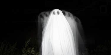 Person dressed as a ghost in a forest, illustrating spooky places with unexplainable, mysterious energy that travelers report