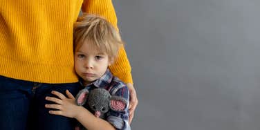 sad toddler hugging mom's leg