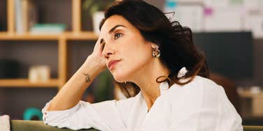 Lonely woman sitting on sofa in quiet home, deep in anxious reflection, wondering if she married the right person — emotional insight into midlife relationship doubt.