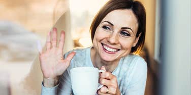 Warm, approachable person offering a small greeting wave, illustrating the natural habits that make someone effortlessly personable.