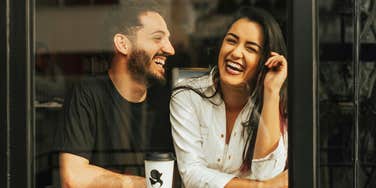 Attentive man listening as a woman opens up laughing showing the art of making conversation and questions that help her share more