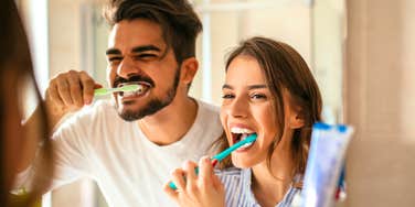 Couple brushing teeth together in the mirror, illustrating relatable everyday moments for people who’ve been in long-term relationships