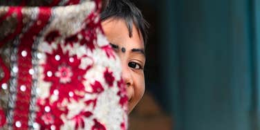 Young Pakistani girl holding her mother’s waist, reflecting the deep bond and pain of being a daughter of a sold mother.