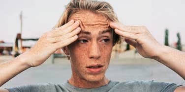 Anxious man holding his temples with wide eyes, when anxiety causes racing heart and stress.