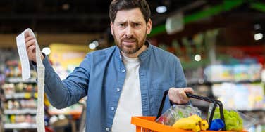 frustrated man holding receipt after grocery shopping