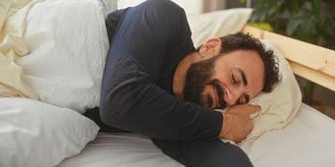 smiling man asleep in bed alone without wife