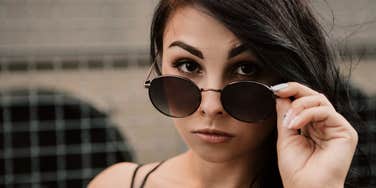 woman who lies lowering her sunglasses