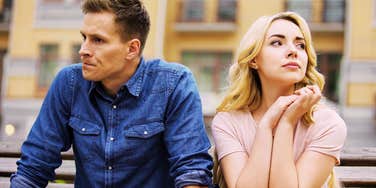 Upset couple sitting on a bench, with the man looking frustrated and the woman crying, illustrating the most dangerous relationship emotion and how it begins to spread between partners.