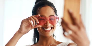 woman taking selfie in sunglasses to post on social media