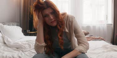 stressed woman sitting in bed early at night looking fearful