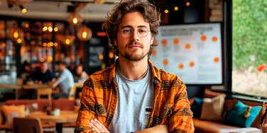 Arrogant man standing with his arms crossed, illustrating the quietly superior body language and dominant behaviors linked to people with a ‘Superman Complex.’