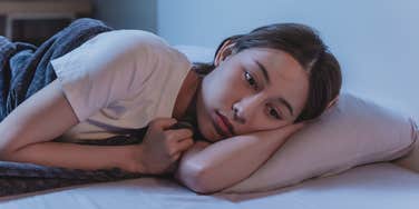 woman lying awake in bed unable to sleep until everything is clean at home