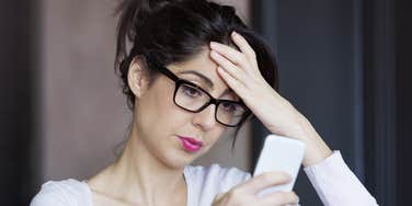 woman looking at phone dreading a call from her parents