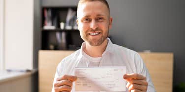 man with old-school principles holding up a check