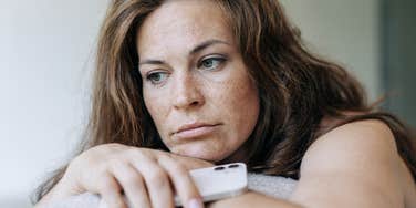 woman holding her phone looking upset