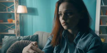 serious woman sitting in dimly lit room thinking