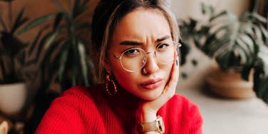 Serious Asian woman in glasses indoors, illustrating psychology skills and mental strategies to help complicated people simplify their thoughts