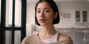 street smart woman standing in her kitchen thinking
