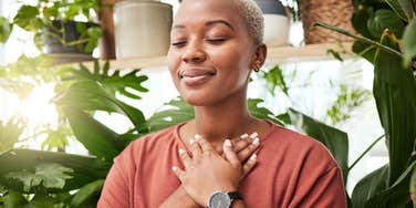 woman with her eyes closed and hands over her chest
