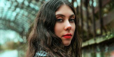 A serene, intuitive woman gazes ahead under a metal frame, capturing the mystery and beauty of discovering psychic abilities and inner power.