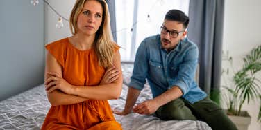 wife upset with husband sitting on the edge of the bed during argument