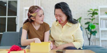 older woman giving teen girl gift