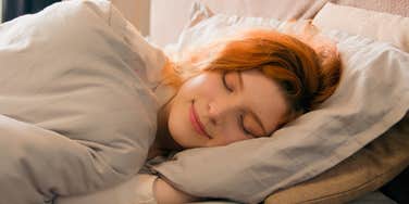 woman laying in bed cuddling her pillow to fall asleep