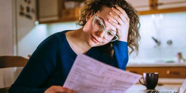 Woman reviewing finances with mixed emotions, illustrating the complex money issues experts say challenge even the happiest relationships