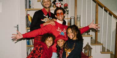 festive family in Christmas sweaters posing happily together, capturing the nostalgic holiday feeling of Christmas movies that signal the season has officially begun.