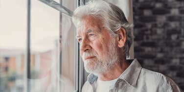 serious boomer man looking out window