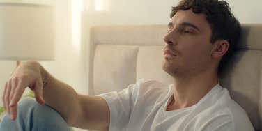 unhappy man sitting up in bed thinking