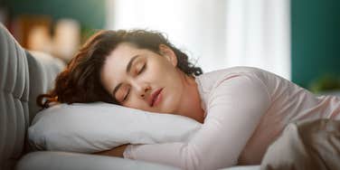 peaceful woman sleeping in bed with window open in background