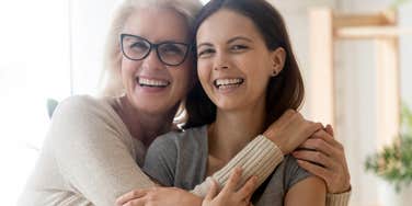 older mom hugging adult daughter bonding