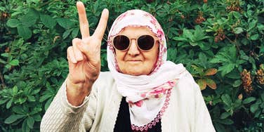 seventy-two-year-old mother wearing sunglasses and a floral scarf flashing a playful peace sign, capturing the bold moment she quit bacon and her forty-year marriage on the same day