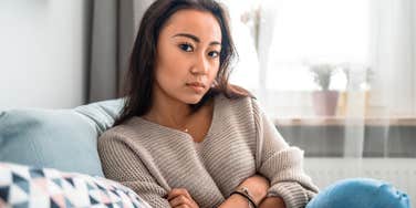 lonely woman sitting on her couch hiding her sadness