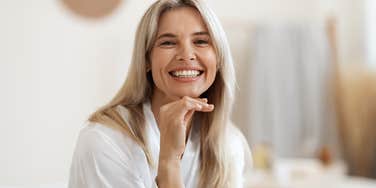 smiling woman sitting in a robe in the bathroom without her phone