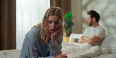 woman upset with husband relaxing in bed