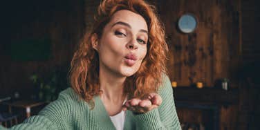 self-centered woman blowing a kiss at home
