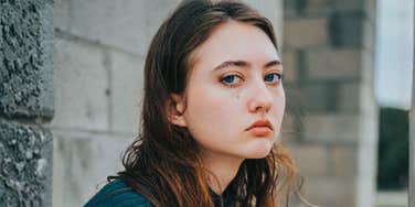 Young woman standing alone with a quiet, searching expression, capturing what it feels like to feel lost during uncertain times and begin finding steadiness again.