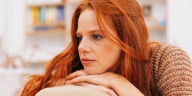 sullen woman sitting at home trying to hide her sadness