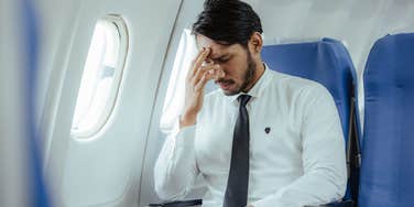 stressed man sitting on plane near window