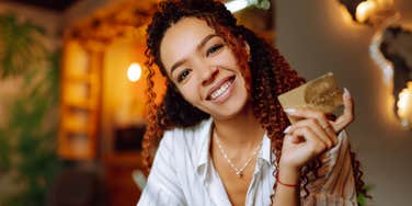 happy frugal woman holding credit card smiling