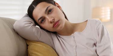 unhappy woman sitting on her couch ruminating