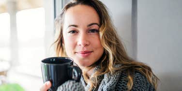 woman taking a calm grounding moment with a warm drink, illustrating simple ways to stay in a good mental place when your partner is being a major bummer.