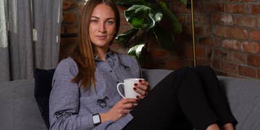 woman sitting on couch in leggings drinking coffee