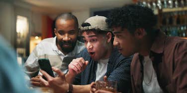 group of men watching sports game on phone