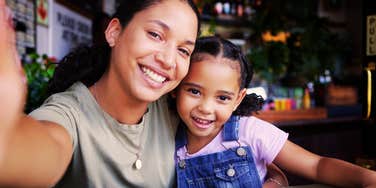 Woman smiling with a young child at a table indoors.