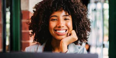 Smiling woman working on a laptop indoors.