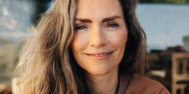 Woman smiling softly with relaxed, confident expression outdoors