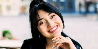 A woman with a bright smile and open posture, appearing approachable, confident, and naturally charming.